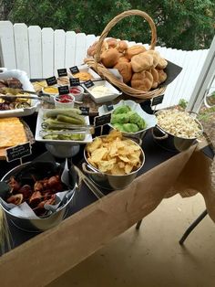 a table filled with lots of food on top of a wooden table next to a white fence