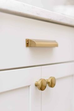 a white cabinet with brass handles and knobs