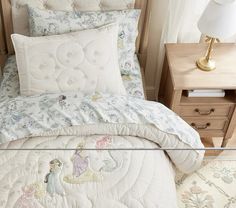 a bed with a white comforter and pillows on top of it next to a night stand