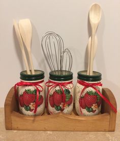 three mason jars with strawberries and whisks in them on a wooden tray