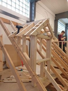 two men are working on the framing of a house that's being built in an unfinished building