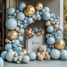 a blue and gold balloon arch with a teddy bear