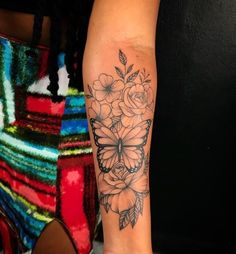 a woman's leg with flowers and butterflies on her left arm, tattoo style