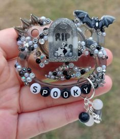 a person is holding some sort of brooch with beads and charms on it that say spooky