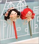 two little dolls are sitting on top of each other, one is holding a pencil