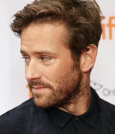 a close up of a person with a beard and black shirt in front of a white background