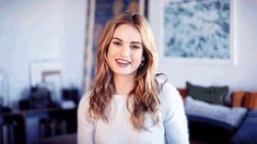 a woman standing in a living room smiling at the camera