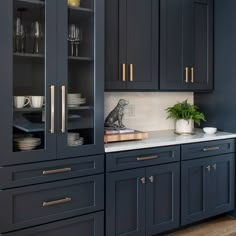 a kitchen with dark blue cabinets and white counter tops, gold pulls on the doors