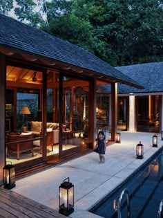 a person standing in front of a house with lanterns on the ground and lights around it