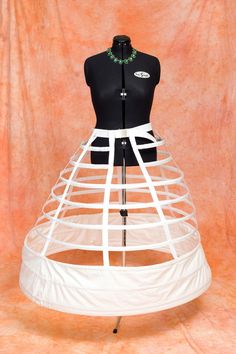 a mannequin wearing a dress made out of white fabric and plastic straps with a green bead necklace