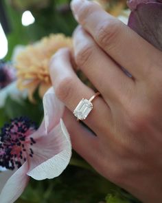 a close up of a person's hand with a ring on top of flowers