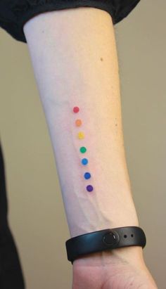 a woman's wrist with a colorful dot tattoo on the left side of her arm