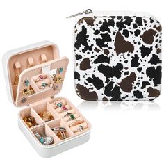 a white and black cow print case with jewelry inside