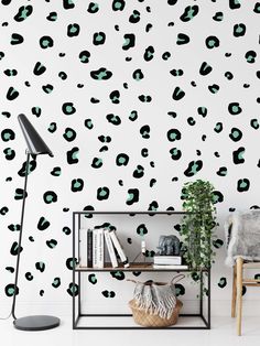 an animal print wallpaper with black and green spots on the wall, next to a book shelf