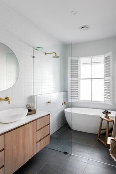 a bathroom with a sink, mirror and bathtub next to a large round window