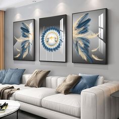 three paintings hang on the wall above a couch in a living room with white furniture