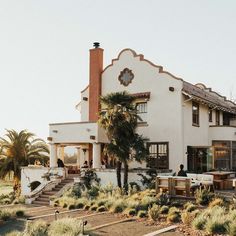 a large white house with palm trees in the front yard and stairs leading up to it