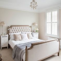 a bedroom with a bed, dresser and chandelier