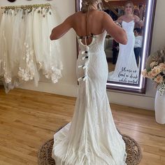 a woman in a wedding dress looking at herself in the mirror with her back to the camera