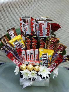 a vase filled with candy and chocolates on top of a table next to flowers