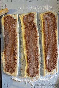 four pastries sitting on top of a pan covered in powdered sugar and cinnamon