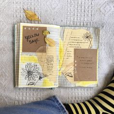 an open notebook with yellow flowers and some writing on the pages next to a woman's legs