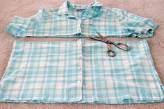 a pair of scissors laying on top of a blue and white checkered shirt