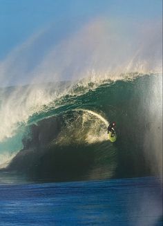 a man riding a wave on top of a surfboard in the ocean under a blue sky