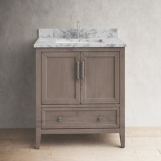 a bathroom vanity with a marble top and two drawers on the bottom, in front of a gray wall