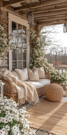 the porch is covered with wicker furniture and flowers