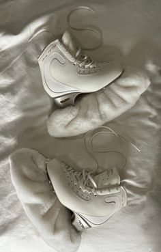 two pairs of white sneakers are laying on a bed