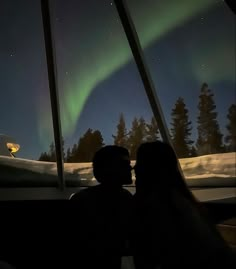 two people are looking out the window at the aurora bore