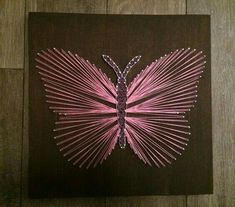 a pink butterfly made out of string on a brown background