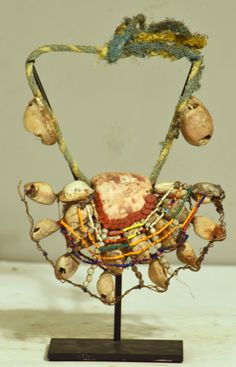 a piece of art that is on top of a wooden stand with beads and other items