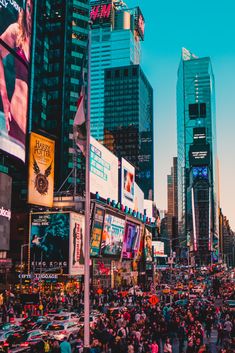 a crowded city street filled with lots of traffic and people walking on the sidewalk near tall buildings