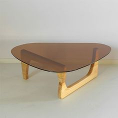 a wooden table with a glass top sitting on a white floor next to a wall