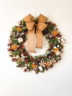 a christmas wreath with pine cones, oranges and other holiday decorations is hung on the wall