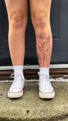 a woman's legs with tattoos on them and white tennis shoes in front of a door