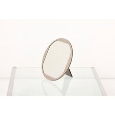 a small mirror sitting on top of a glass table next to a white wall and floor