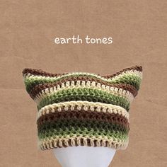 a white mannequin head wearing a green and brown striped knitted hat with the words earth tones on it