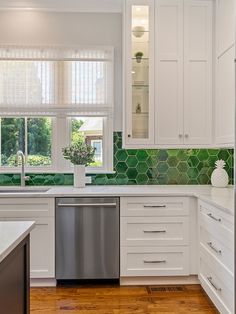 a kitchen with white cabinets and green tiles on the backsplash, stainless steel dishwasher