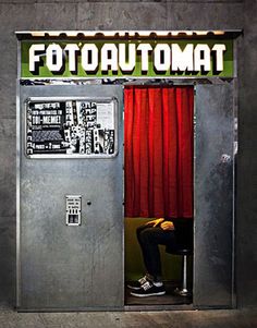 a man sitting on a chair in front of a metal door with the word footautomat above it