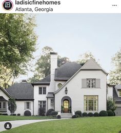 a large white house in the middle of a lush green yard with lots of trees