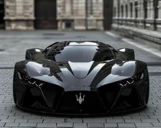 a black and white sports car parked in front of a building on a brick road