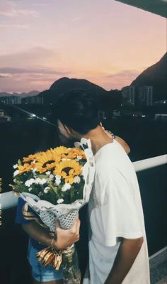 two people kissing each other while holding flowers