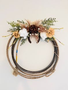 a wreath made out of rope with flowers and feathers