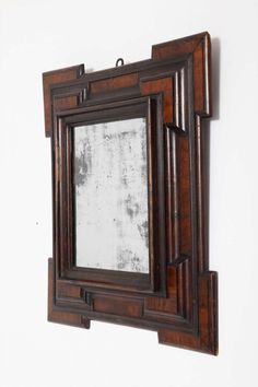 an old mirror hanging on the wall above it's reflection in a wooden frame