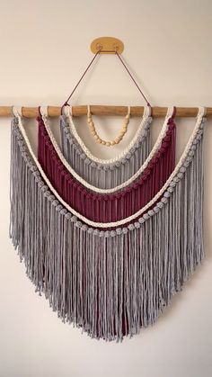 a wall hanging with several different colored fringes on it's sides and a wooden hanger in the middle