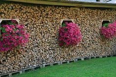 several flowers are hanging on the side of a building made out of firewood logs