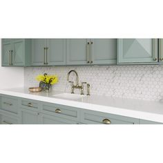 a kitchen with gray cabinets and white counter tops, gold pulls on the faucet